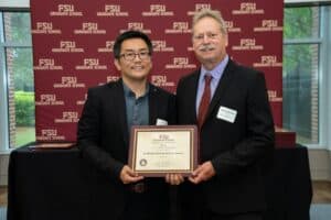 Dr. He stands with the Interim Dean to receive his award.